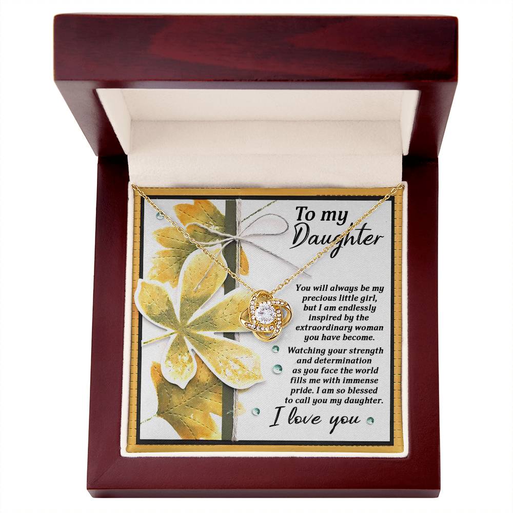 The Daughter-Blessed To Call - Love Knot Necklace, featuring sparkling cubic zirconia crystals and a glowing gold finish, comes in a wooden box with a pristine white interior. Accompanied by a heartfelt note addressed "To my Daughter," it expresses pride in her growth and strength, concluding with "I love you.