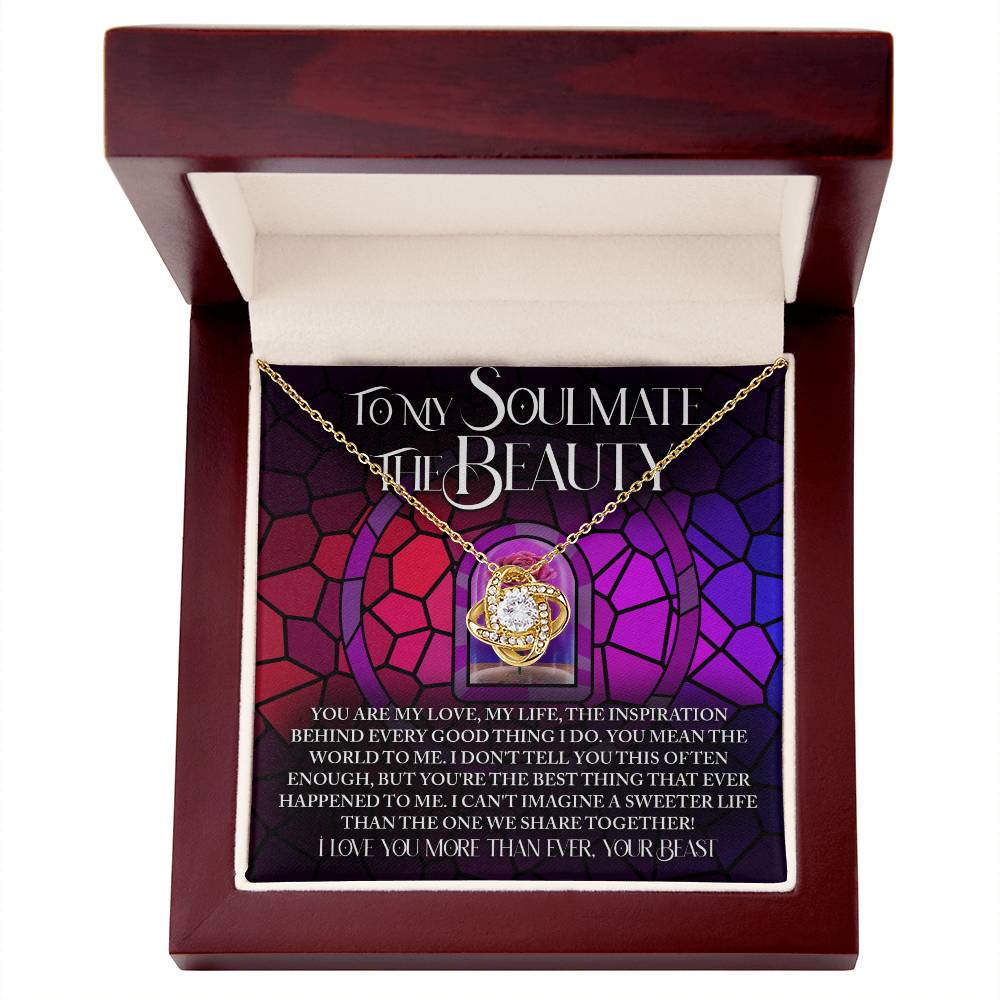 The Soulmate-Sweeter Life Love Knot Necklace, featuring a circular pendant with sparkling cubic zirconia crystals, rests in an open wooden box against a colorful backdrop. With text expressing deep love and appreciation for your soulmate, it's the perfect personalized gift.