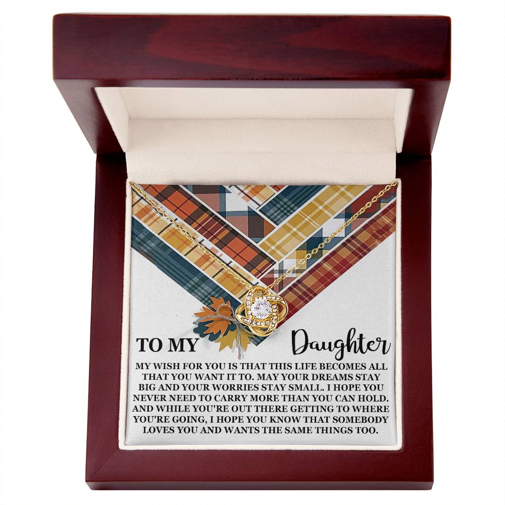 A jewelry box in a wooden case houses the exquisite 14k white gold "Daughter-The Same Things - Love Knot Necklace," adorned with premium cubic zirconia crystals and featuring a heartfelt message for a daughter, wishing for her dreams to stay big, her worries to stay small, and reminding her she is loved.