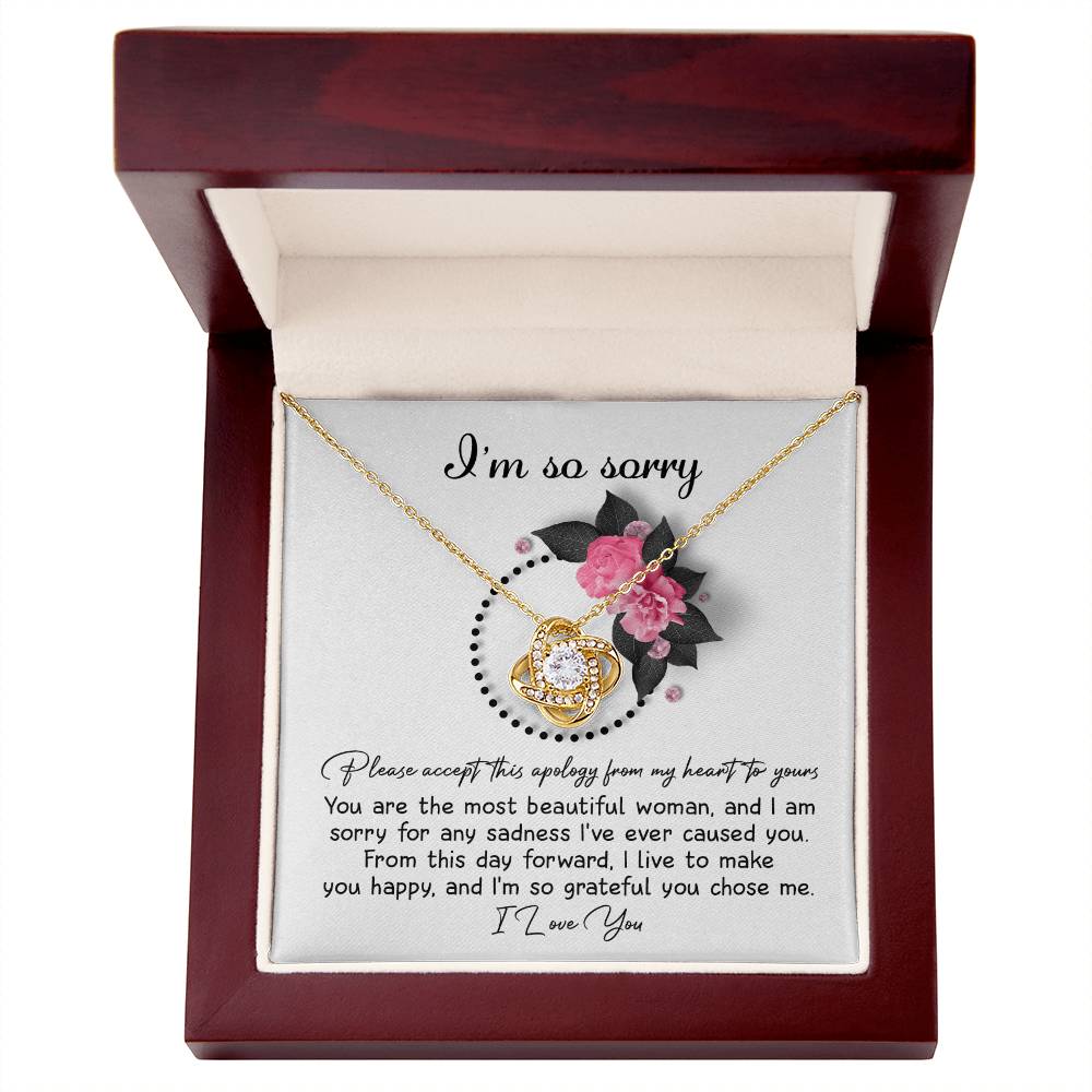 The Sorry-Make You Happy - Love Knot Necklace features a heart-shaped pendant adorned with cubic zirconia crystals, presented in a box decorated with pink flowers and the heartfelt text "I'm so sorry" at the top.