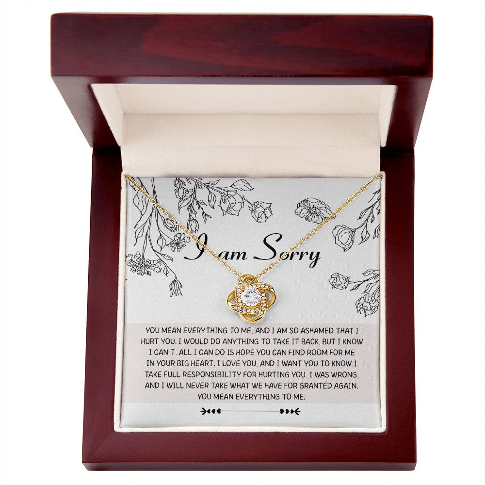 The "Sorry-Your Big Heart - Love Knot Necklace" features a circular pendant adorned with premium cubic zirconia crystals, elegantly presented in an open wooden box. The lid of the box showcases an apology message surrounded by floral illustrations, making it an ideal personalized gift.