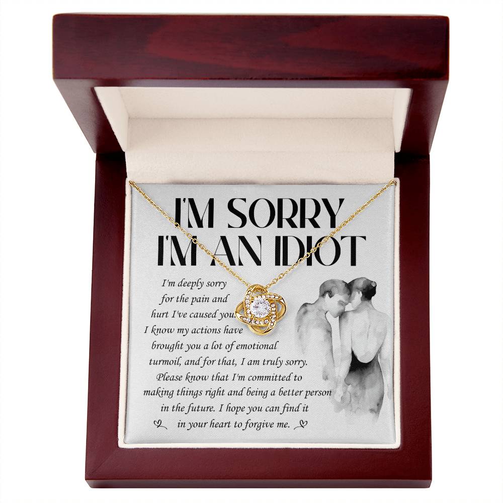 The "Sorry-Emotional Turmoil - Love Knot Necklace" features a gold heart-shaped pendant, presented in a red box. The inside lid contains an apology message expressing remorse for causing emotional pain. A grayscale illustration of a couple embracing is displayed, adding a personalized gift touch adorned with cubic zirconia crystals.