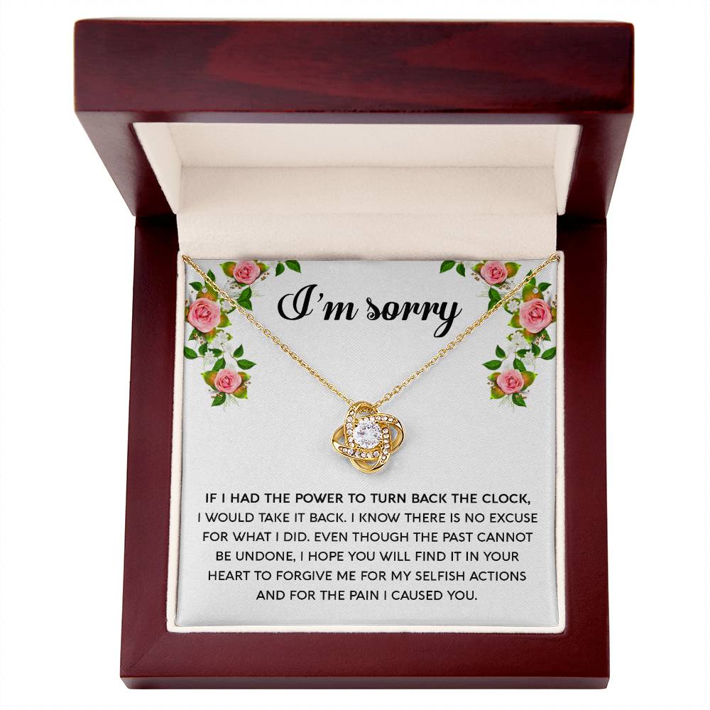 The "Sorry, Make It Right - Love Knot Necklace," featuring a silver intertwined knot pendant adorned with cubic zirconia crystals, is beautifully displayed in a box. The text on the box reads, "I’m sorry," with an apology message below, framed by a floral border in the top corners.