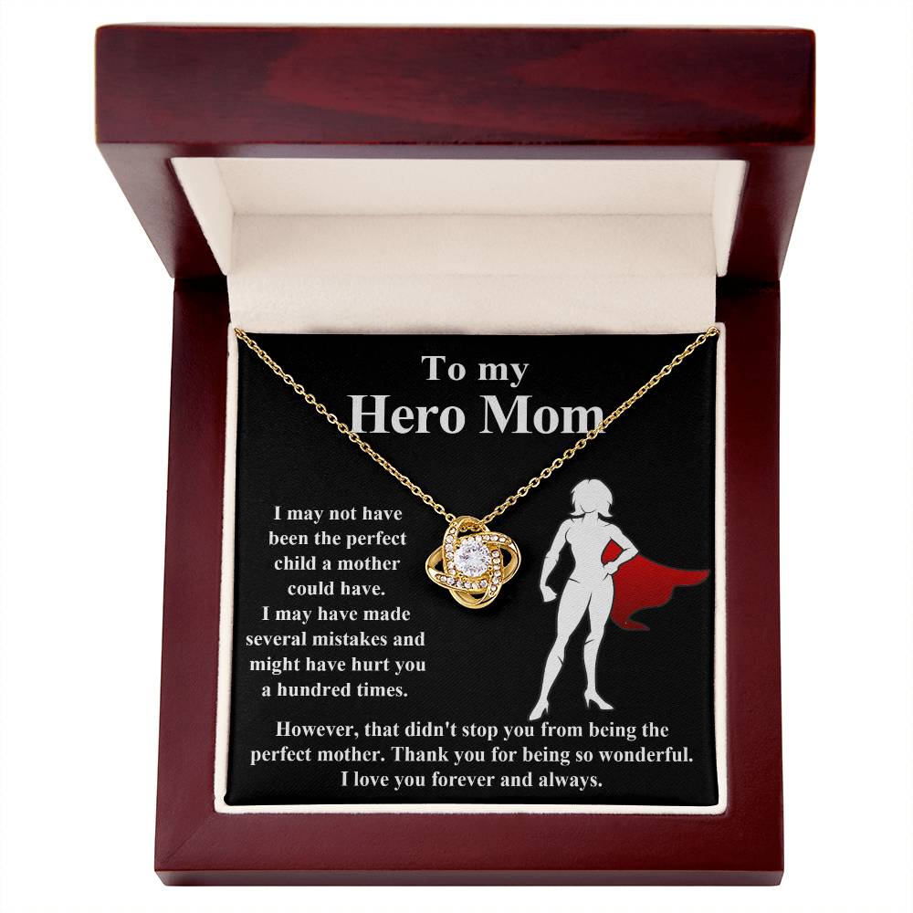 The "To Mom, The Perfect Mother - Love Knot Necklace" is elegantly displayed inside a wooden box. The inscription reads: "To my Hero Mom," accompanied by a heartfelt note of love and gratitude. The pendant sparkles beautifully with cubic zirconia crystals for added brilliance.