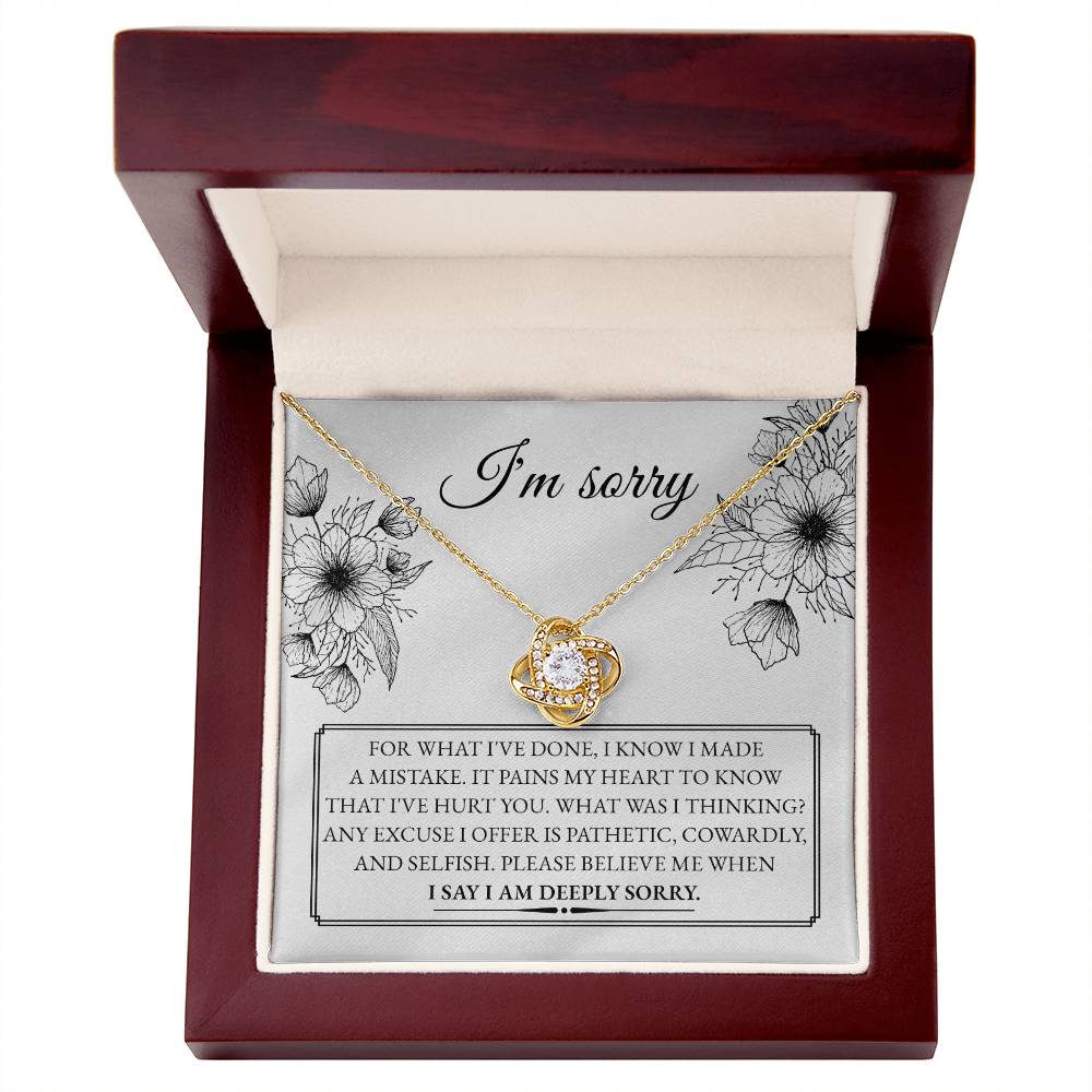 A "Sorry-Made A Mistake - Love Knot Necklace" features a box with a heartfelt apology message. The white gold finish and cubic zirconia crystals shimmer, as the text expresses deep regret and sorrow for causing hurt, describing the actions as pathetic, cowardly, and selfish, pleading for forgiveness.