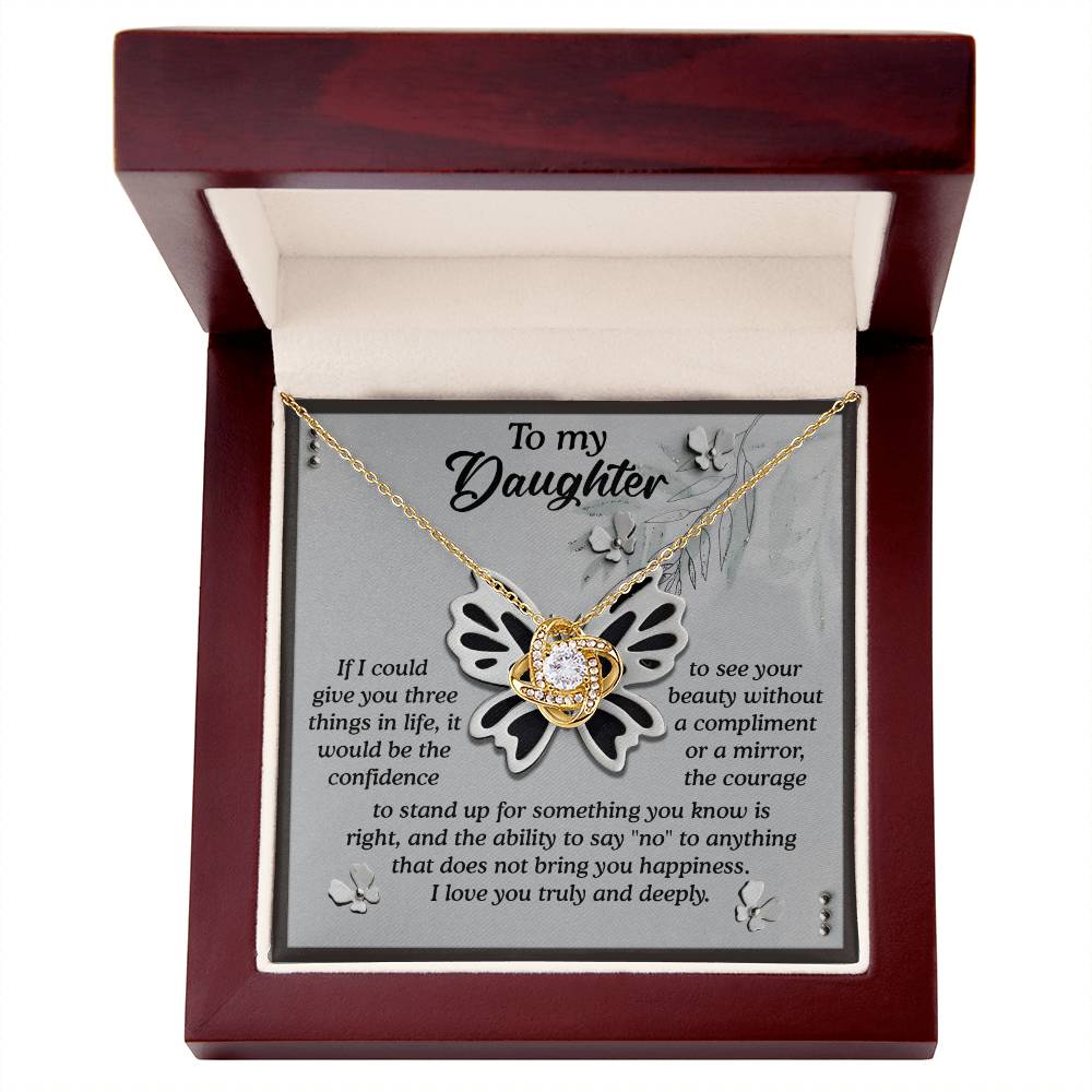 The Daughter-See Your Beauty - Love Knot Necklace, featuring a gold pendant adorned with premium cubic zirconia crystals, is beautifully presented in a wooden box inscribed with "To my Daughter" and followed by a heartfelt message about love, confidence, courage, and happiness.