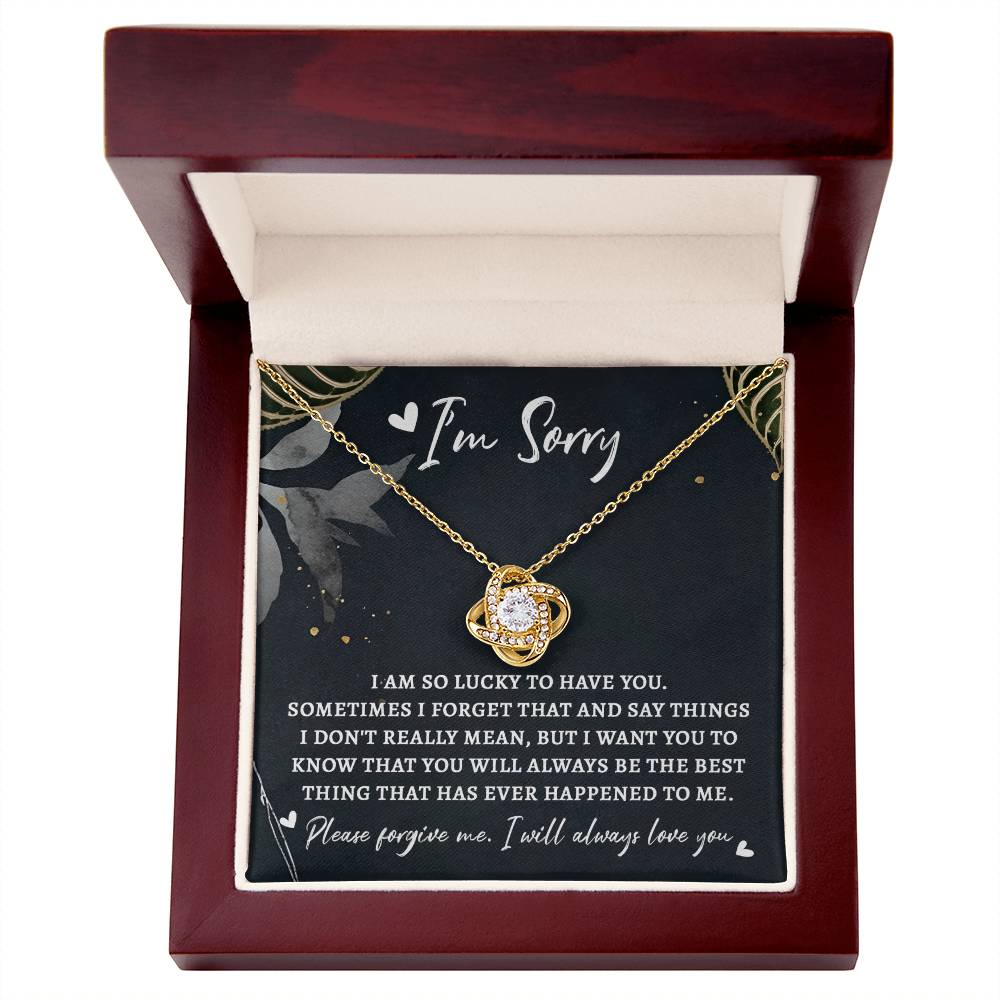 A Sorry-The Best Thing - Love Knot Necklace with a planet-shaped pendant displayed in an open wooden box. The box, featuring a message starting with "I'm Sorry" followed by a heartfelt apology, makes for the perfect personalized gift.