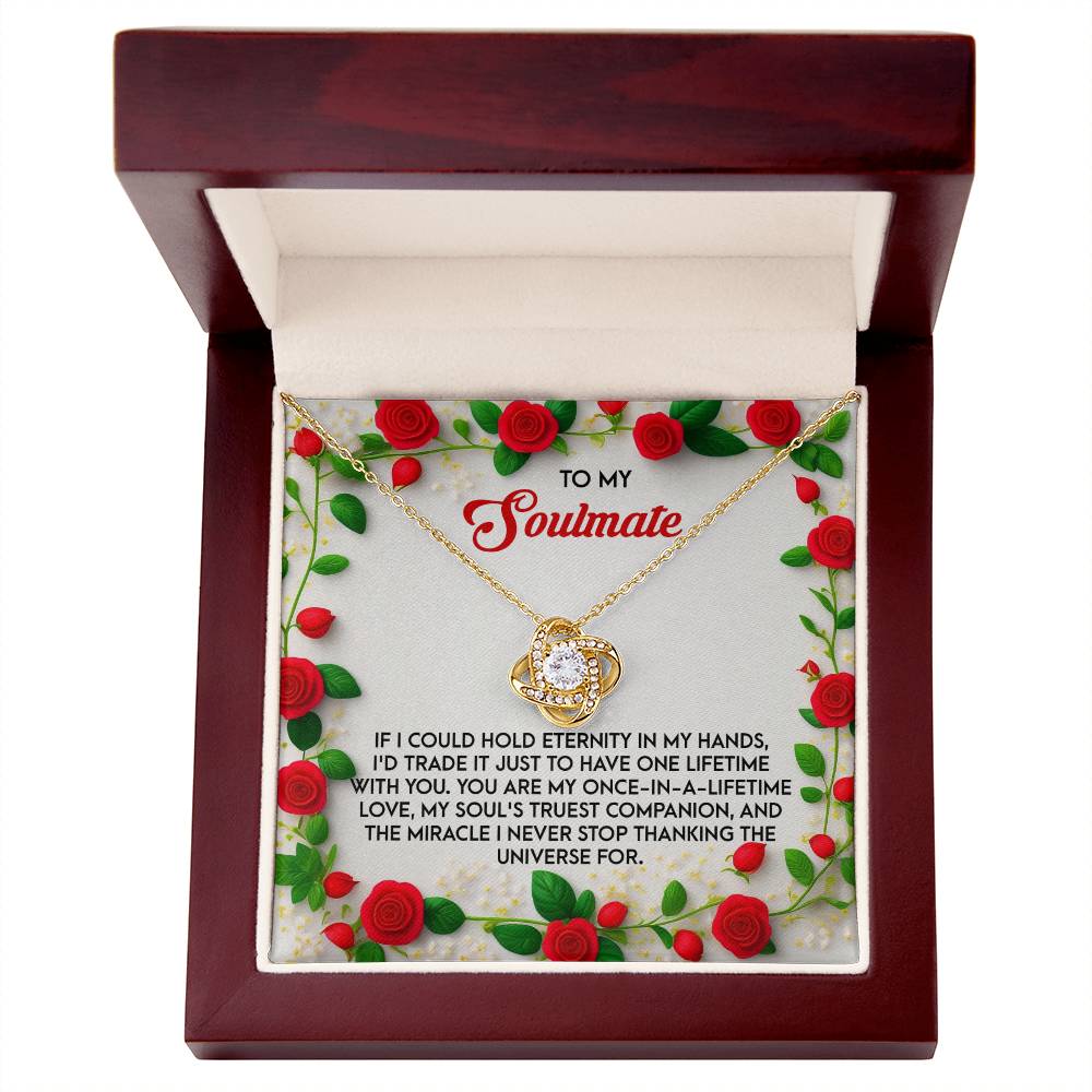 The Soulmate-One Lifetime - Love Knot Necklace features a round white gold pendant elegantly showcased in a decorative box. Inside, red roses and a heartfelt message for a soulmate accompany the dazzling cubic zirconia pendant.