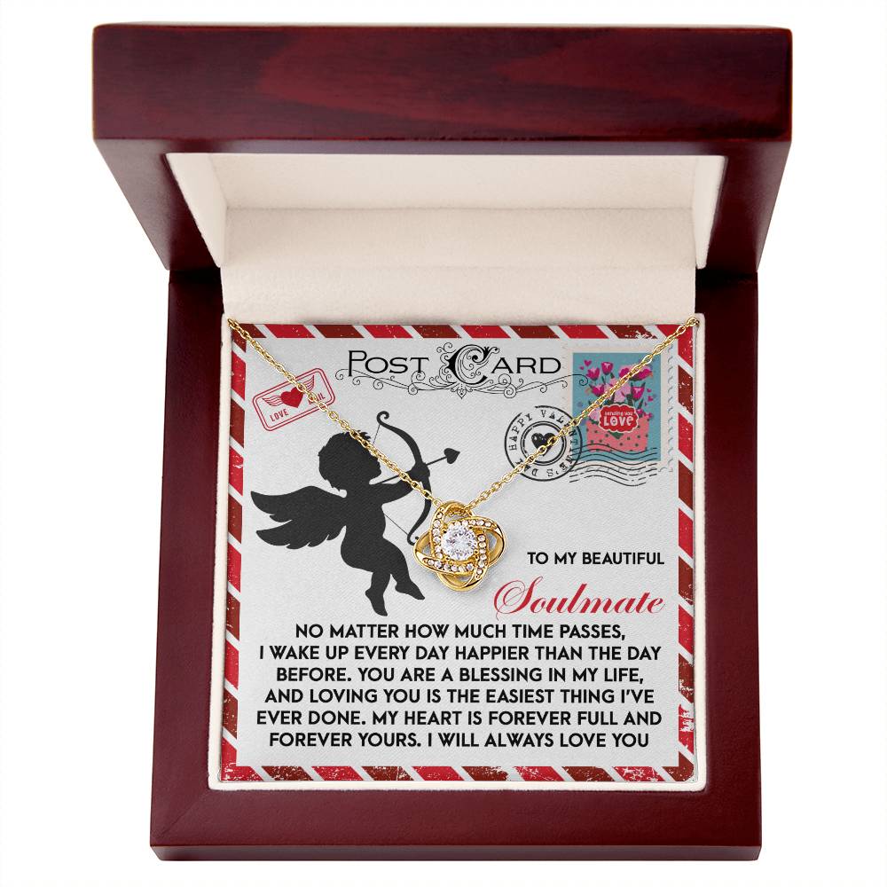 Open wooden box with the Soulmate-Forever Yours - Love Knot Necklace, set against a postcard-themed backdrop. Featuring romantic messages about love and soulmates, this personalized gift sparkles with cubic zirconia, capturing timeless elegance and heartfelt sentiment.