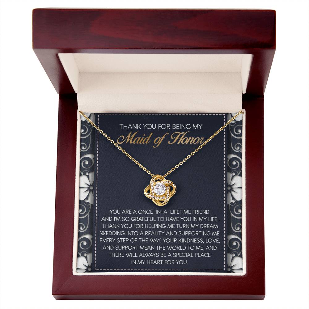 The "To Maid of Honor, World To Me - Love Knot Necklace" features a heart-shaped pendant adorned with Cubic Zirconia Crystals. It comes beautifully packaged in a box that includes an inscribed thank-you note, expressing heartfelt gratitude to the Maid of Honor, making it a perfect personalized gift.