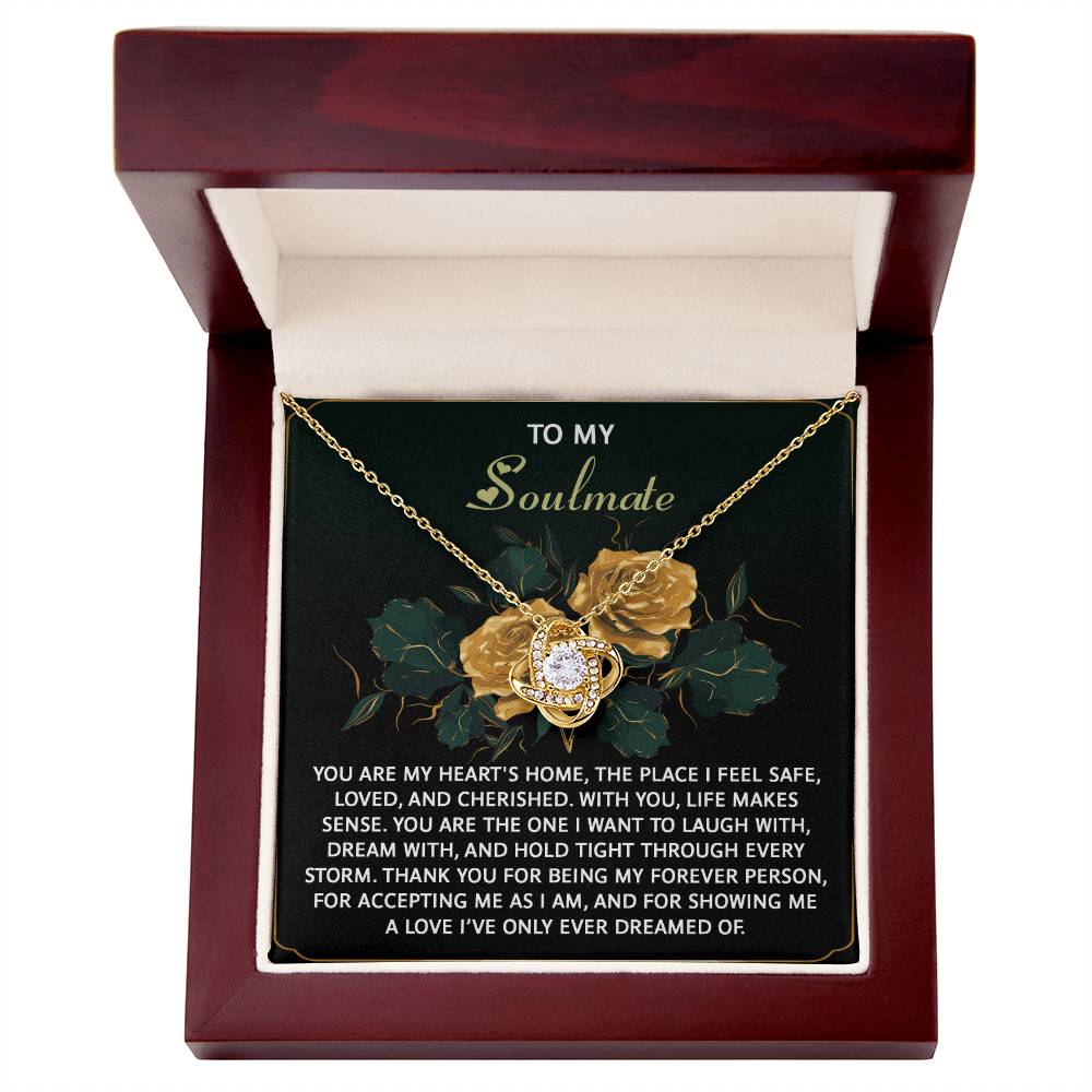The Soulmate-Forever Person Love Knot Necklace is a beautiful gold piece with a floral design, featuring cubic zirconia crystals. It comes in a wood box with a heartfelt message for your soulmate, emphasizing love, laughter, and gratitude—a genuinely personalized gift for someone special.