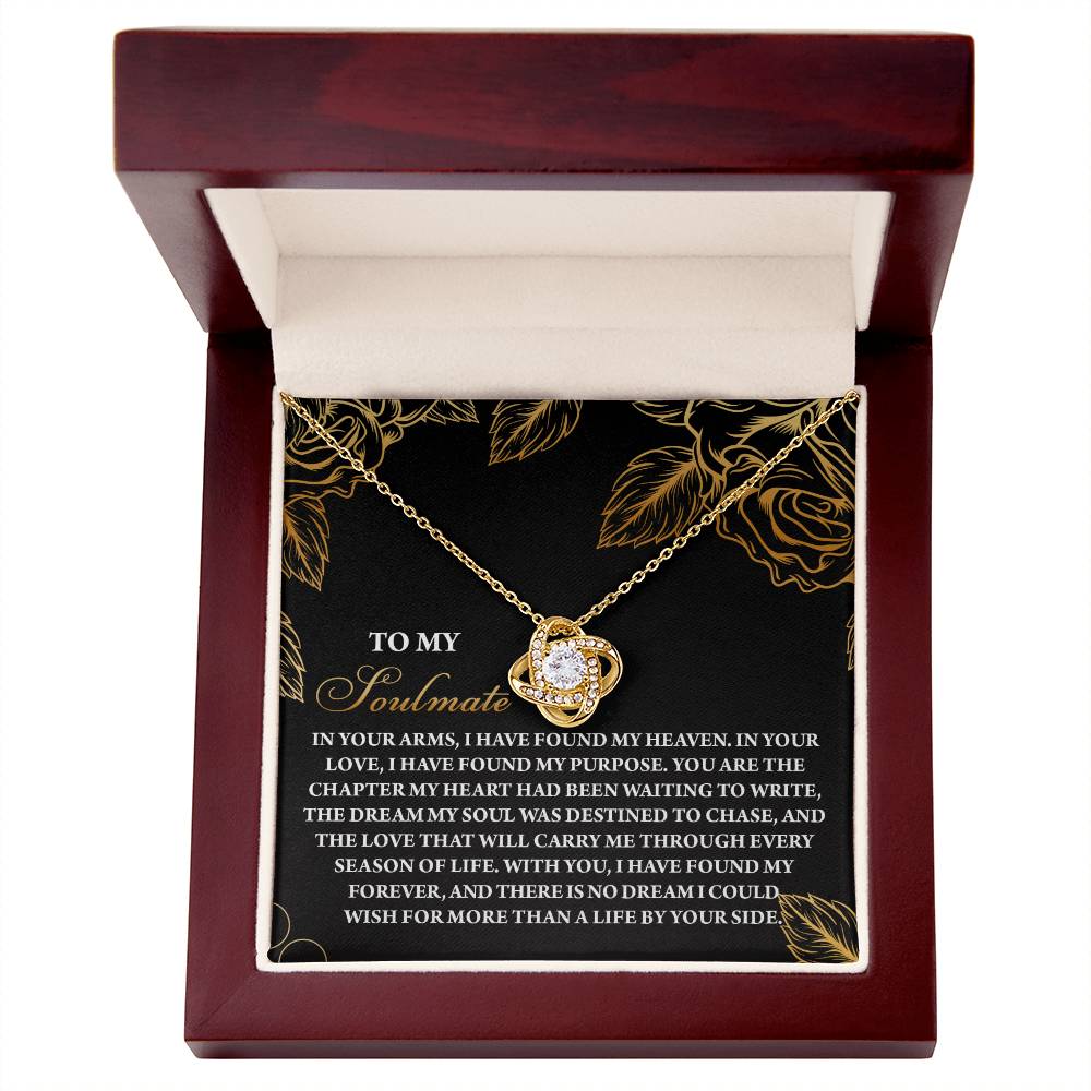 The Soulmate-By Your Side Love Knot Necklace with pendant is showcased in an open maroon box, inscribed with floral designs. Enhanced by cubic zirconia crystals, it makes a perfect personalized gift.