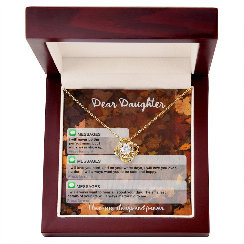 Daughter-Perfect Mom - Love Knot Necklace features a central gemstone in a red jewelry box. The yellow gold finish and cubic zirconia crystals add an elegant touch. The box lid features a heartfelt message to a daughter, ensuring constant love and support.