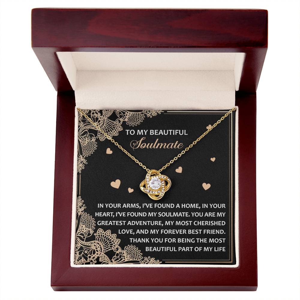 The Soulmate-Beautiful Part - Love Knot Necklace is displayed in a wooden box with a heart pendant, featuring a yellow gold finish adorned with cubic zirconia crystals. The lid reads "To My Beautiful Soulmate," accompanied by a heartfelt message.