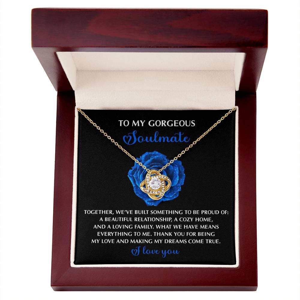 The Soulmate-Dreams Come True - Love Knot Necklace, featuring sparkling cubic zirconia and intertwined rings, rests in an open box. The inside cover reads: "To my gorgeous soulmate," with a heartfelt message ending in "I love you." This personalized gift perfectly expresses devotion.