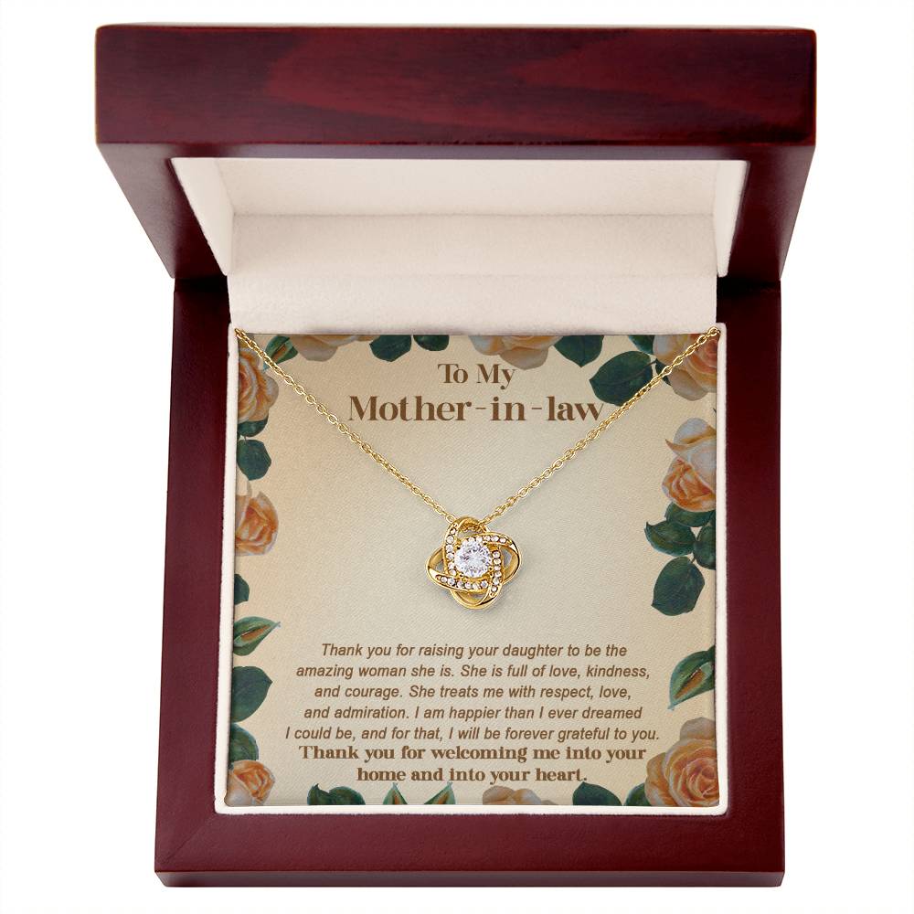 The "To Mother-in-law, Grateful To You - Love Knot Necklace," featuring a central gemstone and adorned with shimmering cubic zirconia crystals, is beautifully presented in an open wooden box. The inner lid displays a heartfelt message for a mother-in-law.