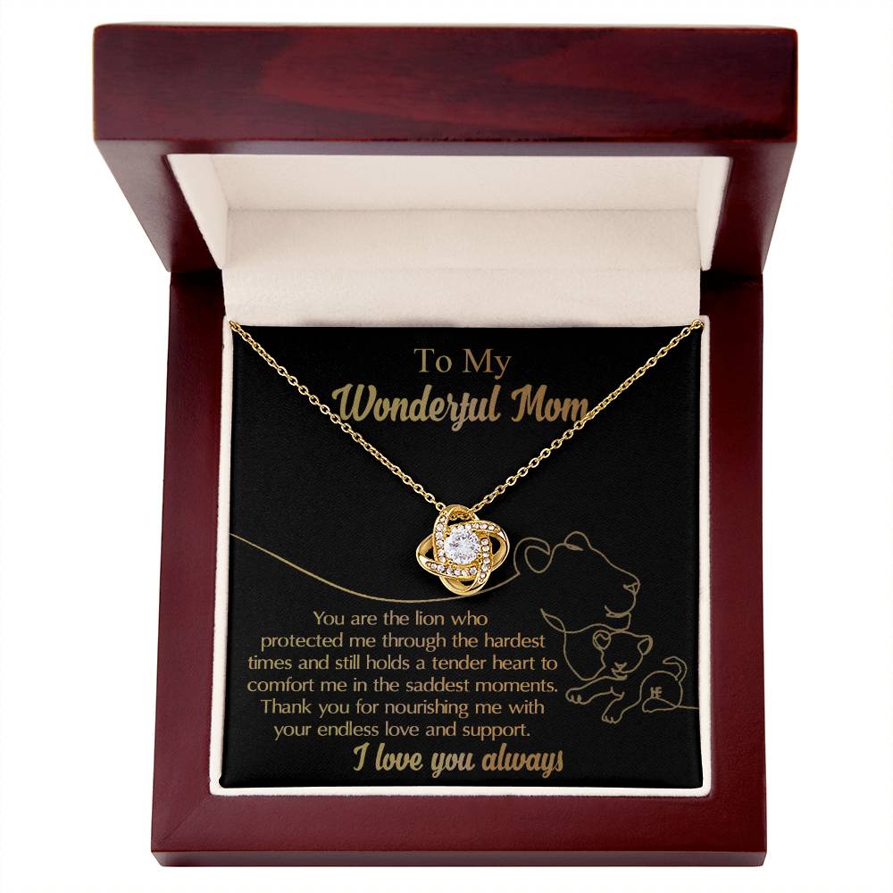 Product Name: "To Mom, The Lion - Love Knot Necklace"
A "To Mom, The Lion - Love Knot Necklace" with a gleaming pendant is displayed in an open wooden jewelry box. Crafted from white gold and adorned with cubic zirconia, the necklace is dedicated to a mother with a heartfelt inscription of love and appreciation on the lid.