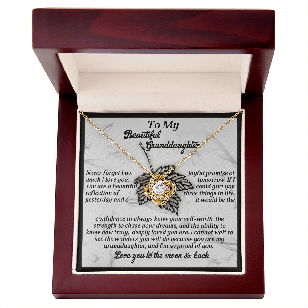 A Love Knot Necklace, featuring a circular pendant adorned with cubic zirconia stones, is beautifully nestled in a wooden box. The included card reads "To My Beautiful Granddaughter" and comes with a touching message. This necklace is aptly named the Granddaughter-Deeply Loved - Love Knot Necklace.