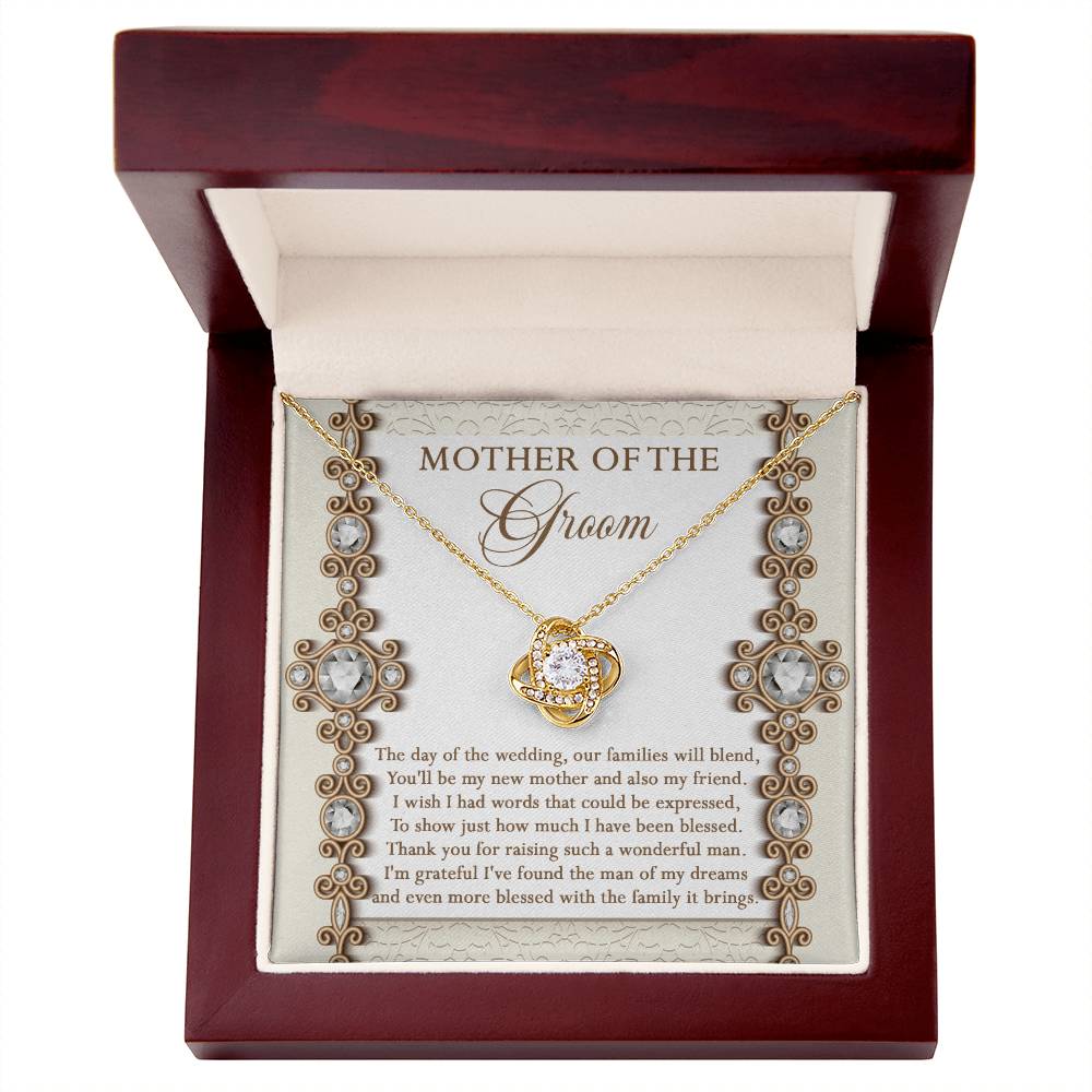 To Mom Of Groom, New Mother - Love Knot Necklace with an interlocking heart pendant, adorned with cubic zirconia crystals, on a card reading: “Mother of the Groom” and a heartfelt message appreciating the groom's mother. Available in white gold or yellow gold finish.