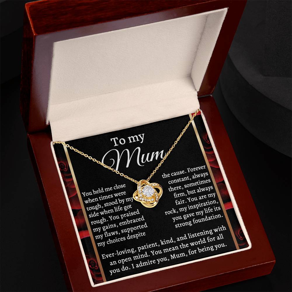 The Mom-By My Side - Love Knot Necklace, featuring an interlocking heart pendant with cubic zirconia crystals, is displayed in an open brown jewelry box. A heartfelt message "To my Mum" expresses gratitude and admiration.
