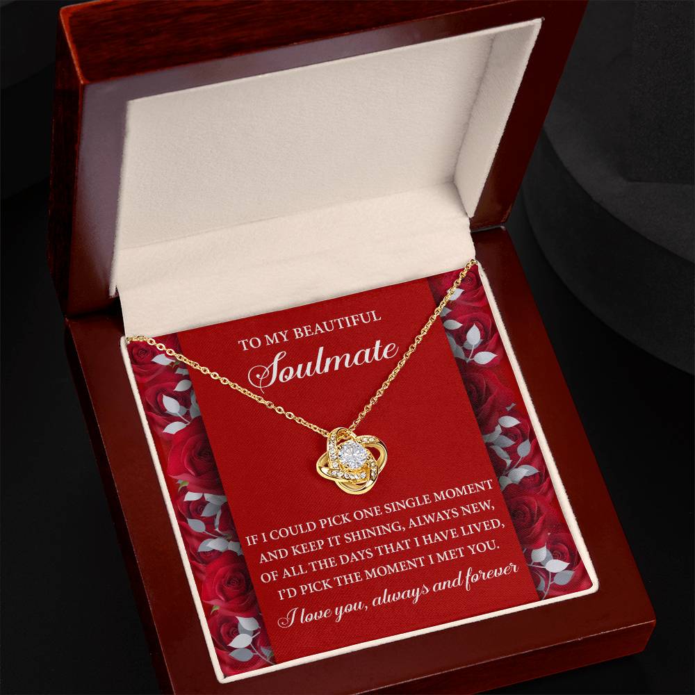 The Soulmate-Keep It Shining Love Knot Necklace, featuring cubic zirconia, is elegantly presented in a jewelry box on a red paper background with a romantic message.