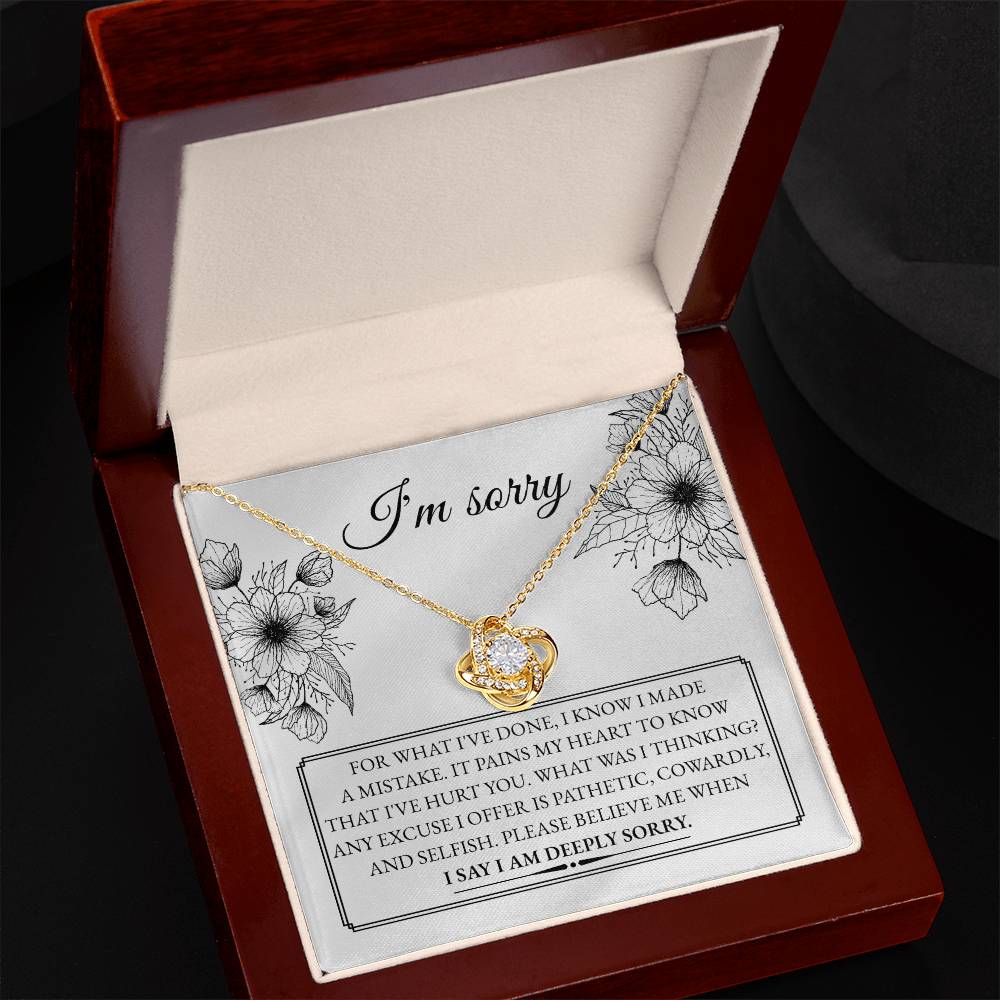 A "Sorry-Made A Mistake - Love Knot Necklace" features a box with a heartfelt apology message. The white gold finish and cubic zirconia crystals shimmer, as the text expresses deep regret and sorrow for causing hurt, describing the actions as pathetic, cowardly, and selfish, pleading for forgiveness.