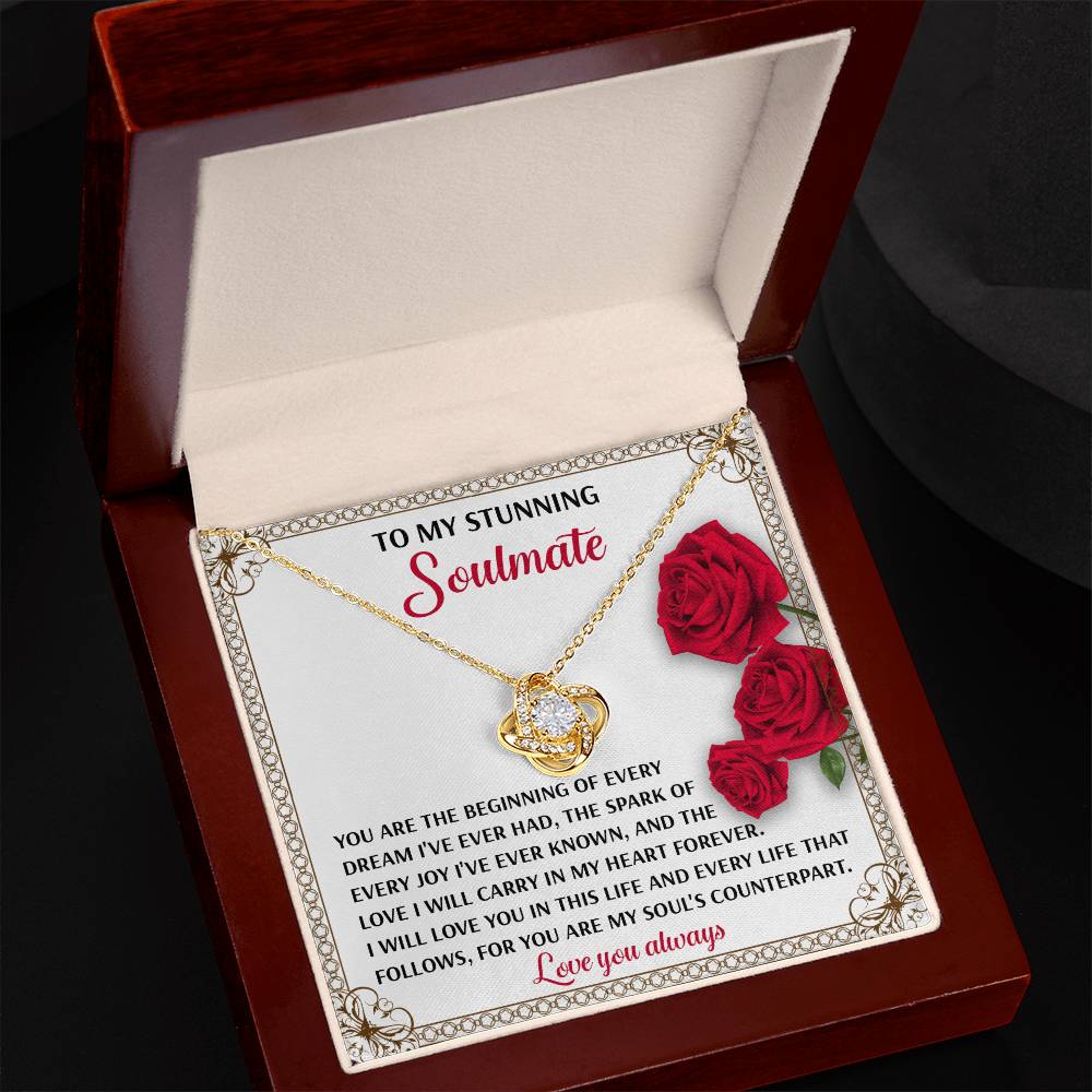 The Soulmate-Soul's Counterpart - Love Knot Necklace features a gold-finished, heart-shaped pendant with cubic zirconia in a box with a card reading: "To my stunning soulmate," accompanied by red roses and a heartfelt message, for an elegant expression of love.