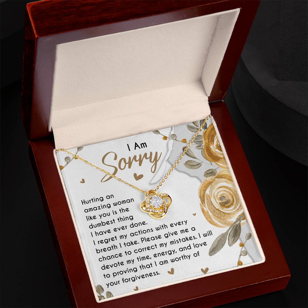 The Sorry-Amazing Woman - Love Knot Necklace, adorned with cubic zirconia crystals, rests inside a wooden gift box. The box lid interior displays an apology note to an "amazing woman," making this classic gift truly special.