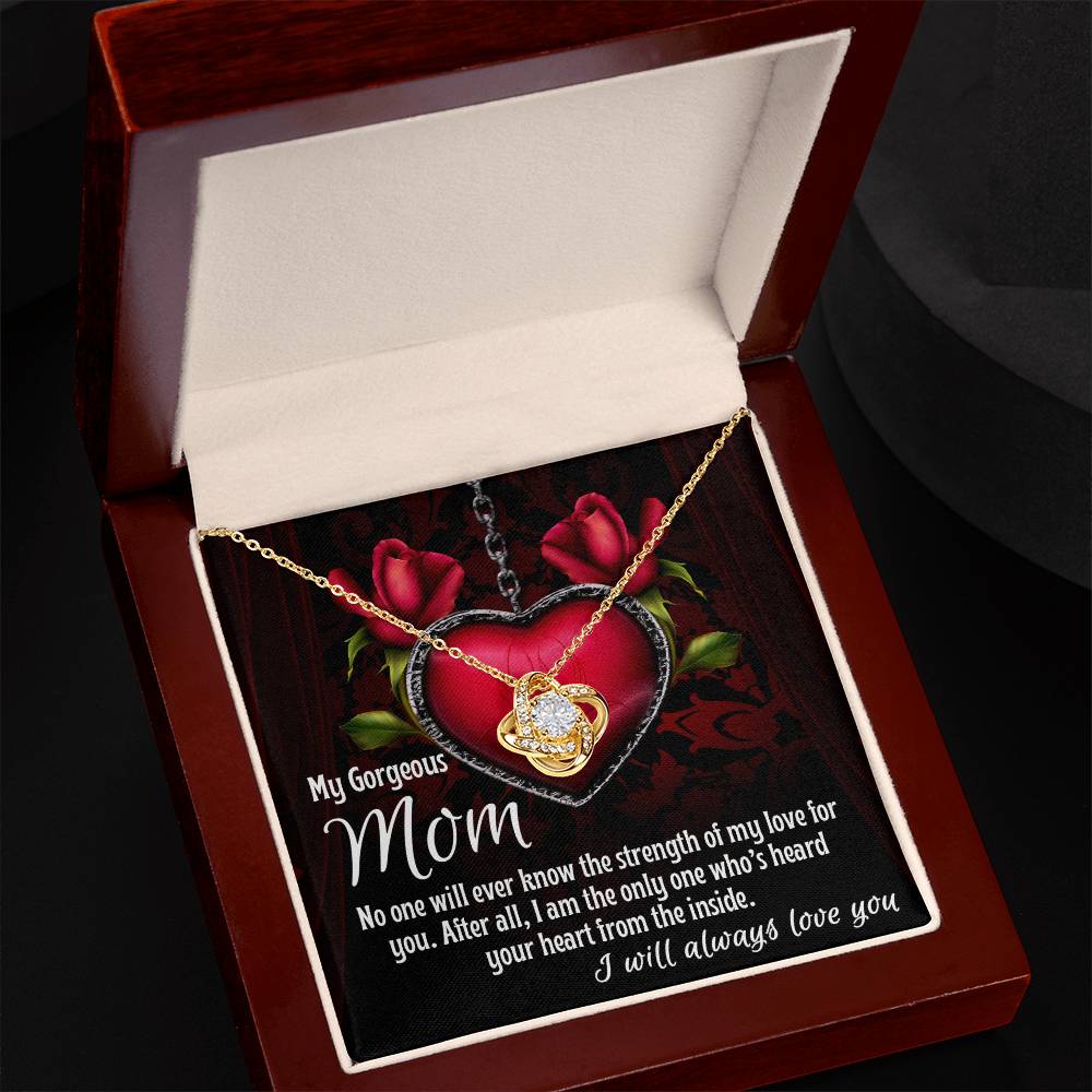 The "Almost Sold Out" To Mom, Heard Your Heart - Love Knot Necklace, adorned with sparkling cubic zirconia crystals and featuring a heartfelt message for "Mom" on the inside lid, is displayed in an open jewelry box. This gold heart-shaped necklace with a crystal pendant makes for an elegant and sentimental surprise.