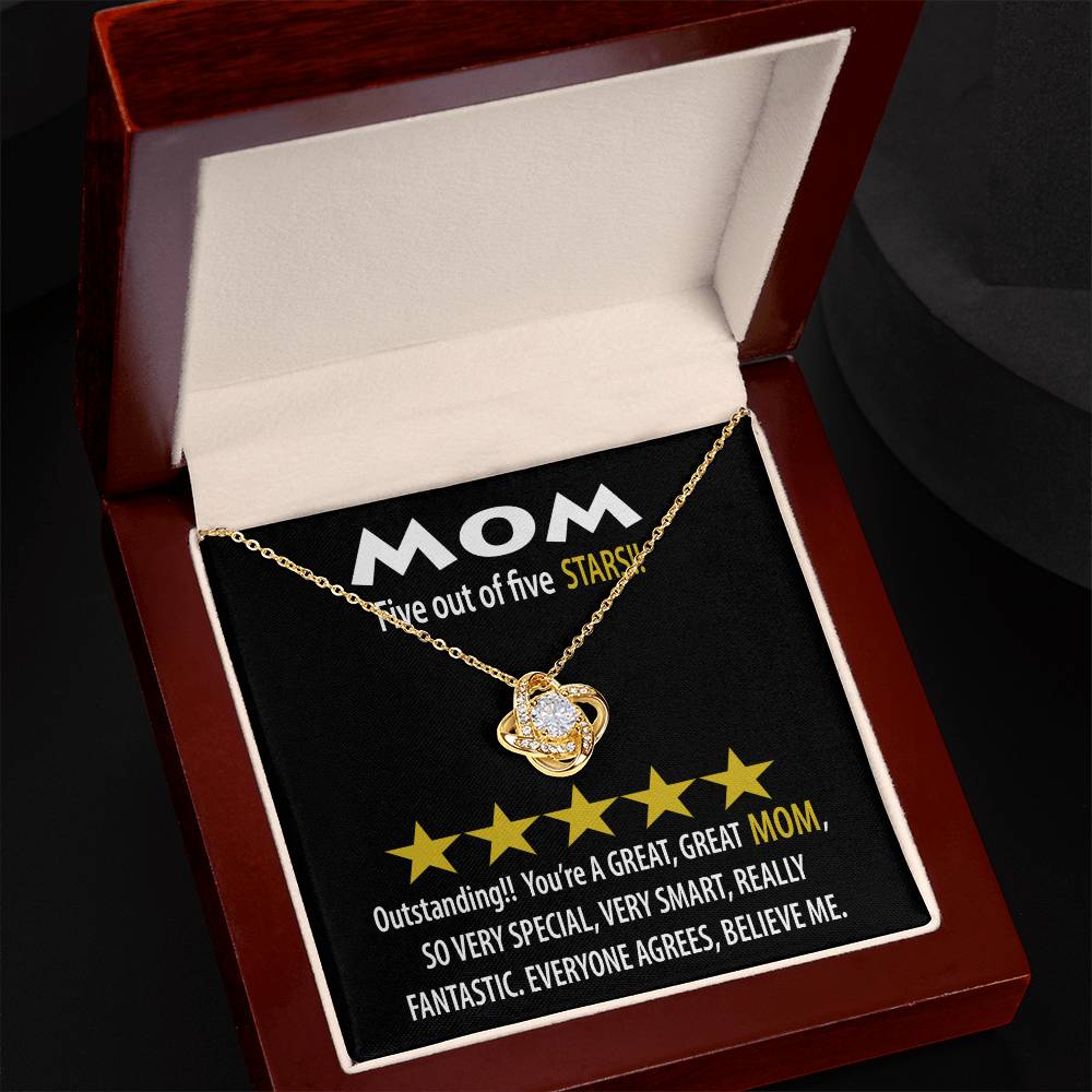 The Mom-Five Stars Love Knot Necklace, featuring a heart-shaped pendant, is beautifully presented in a wooden box with a black interior that highlights "MOM" alongside five-star ratings and words like "great," "smart," and "fantastic." This personalized gift radiates love like a cubic zirconia.