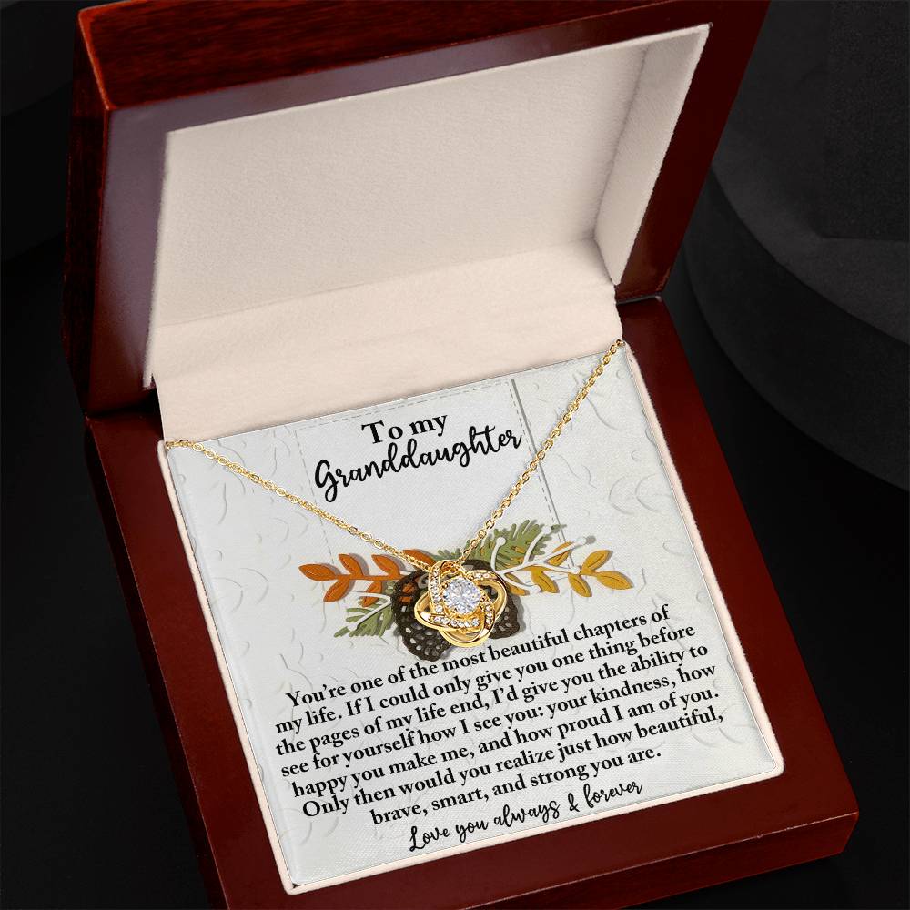 The Granddaughter-How Beautiful - Love Knot Necklace, with a gold finish, rests elegantly in a gift box and features a heartfelt message addressed to a granddaughter. Adorned with sparkling cubic zirconia, the necklace beautifully expresses love and admiration.