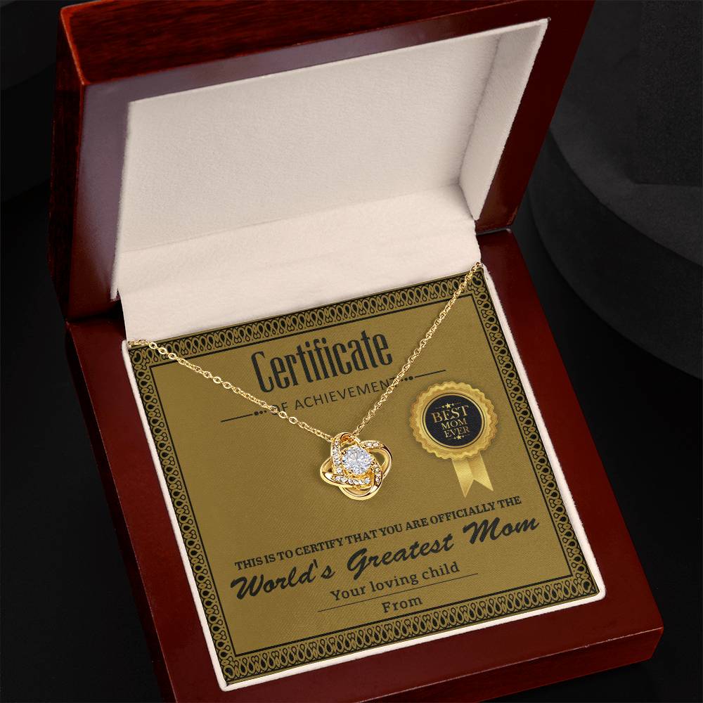 The Mom-Certificate Of Achievement - Love Knot Necklace features cubic zirconia crystals and comes in a wooden box with a "Best Mom" gold seal and "World's Greatest Mom" certificate, making it an ideal gift for any cherished mom.