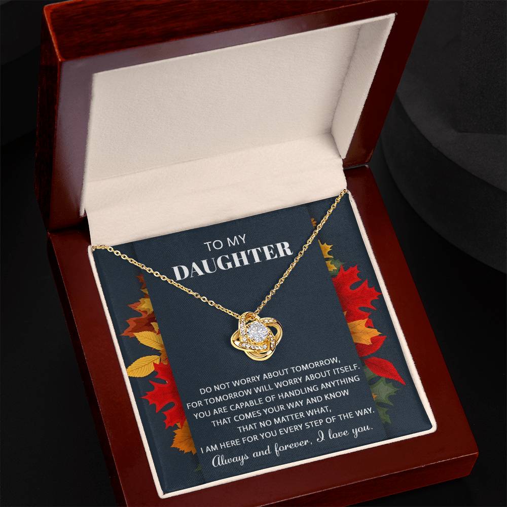 A Daughter-Comes Your Way - Love Knot Necklace with a heart pendant is displayed in an open wooden box. The inside of the lid contains an inspirational message titled "To My Daughter." The necklace, adorned with cubic zirconia crystals, shines brilliantly with its white gold finish.