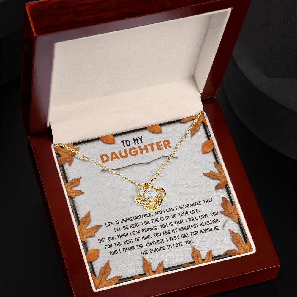 Open box showcasing a Daughter-My Greatest Blessing - Love Knot Necklace, featuring an interlocking heart pendant adorned with cubic zirconia crystals, symbolizing the unbreakable bond. The message inside the box lid reads "To My Daughter" and is surrounded by autumn leaf decorations.
