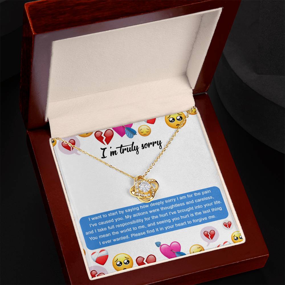 The Sorry-How Deeply Sorry - Love Knot Necklace, presented in an open box with an apology message and adorned with various heart and emoji designs around the text, features premium cubic zirconia crystals for added sparkle.