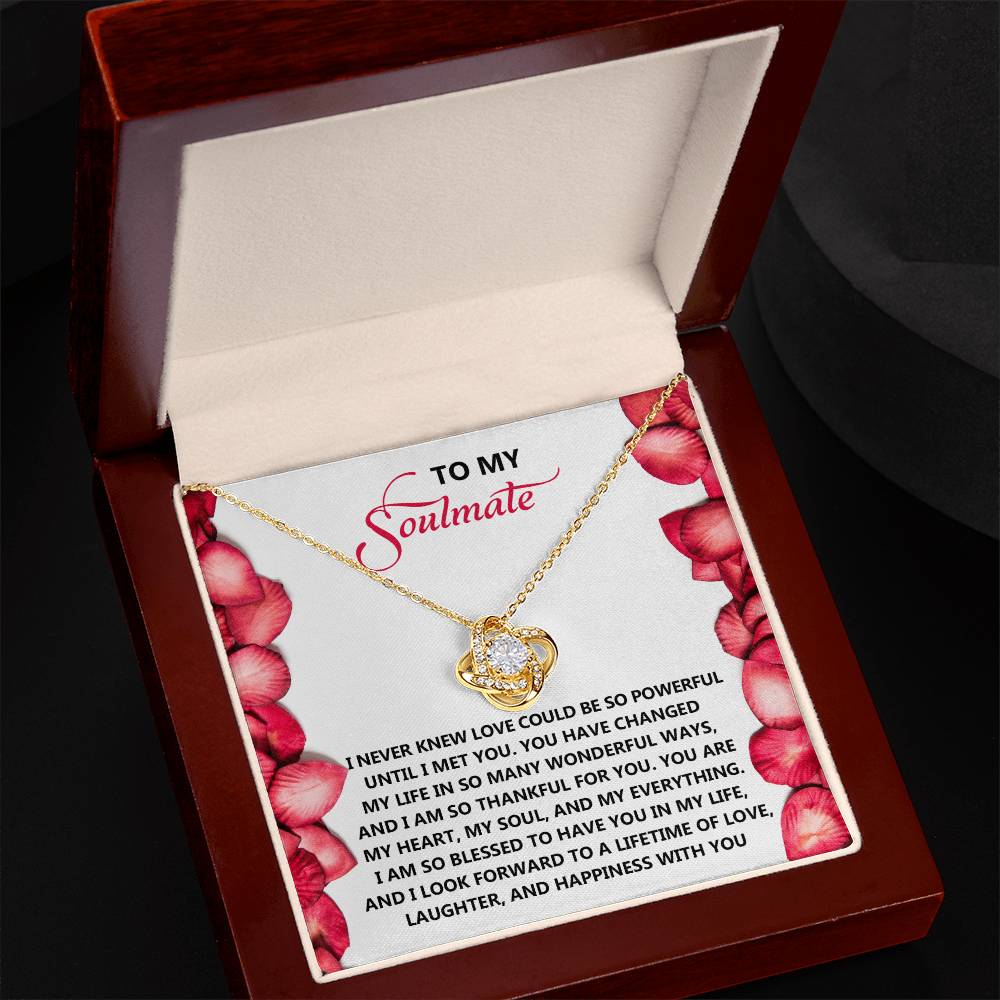 The Soulmate-Until I - Love Knot Necklace is a personalized gift featuring a heart-shaped pendant with sparkling cubic zirconia crystals. It comes in a box with a heartfelt message to your soulmate on the inside lid, surrounded by delicate red rose petals.