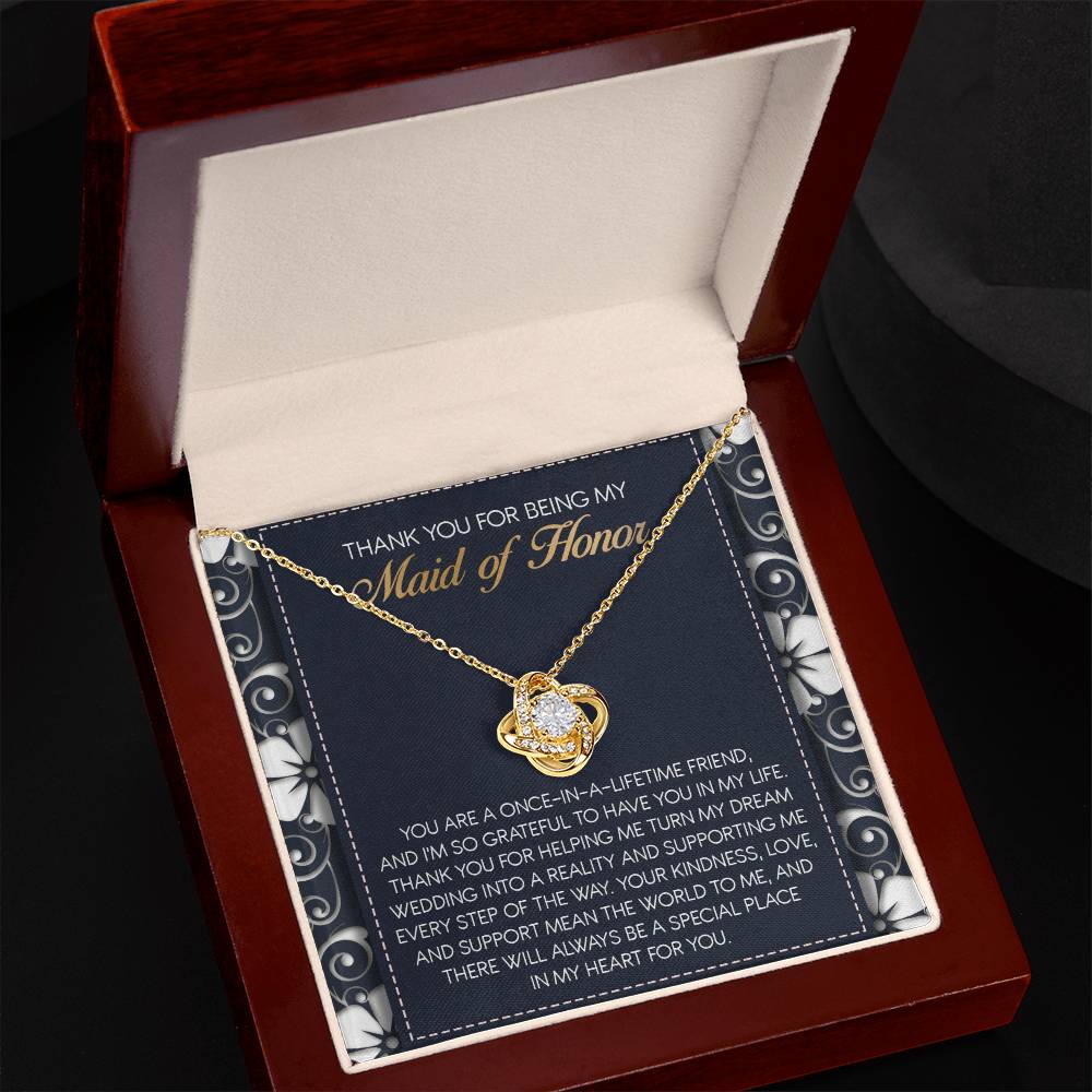 The "To Maid of Honor, World To Me - Love Knot Necklace" features a heart-shaped pendant adorned with Cubic Zirconia Crystals. It comes beautifully packaged in a box that includes an inscribed thank-you note, expressing heartfelt gratitude to the Maid of Honor, making it a perfect personalized gift.