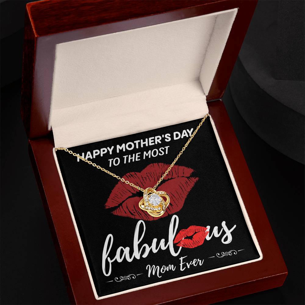 The "To Mom, The Most Fabulous - Love Knot Necklace" features a heart pendant nestled in a red and black box. The packaging includes an interior message that reads, "Happy Mother's Day to the most fabulous mom ever," set against a backdrop decorated with red lip prints and cubic zirconia crystals.