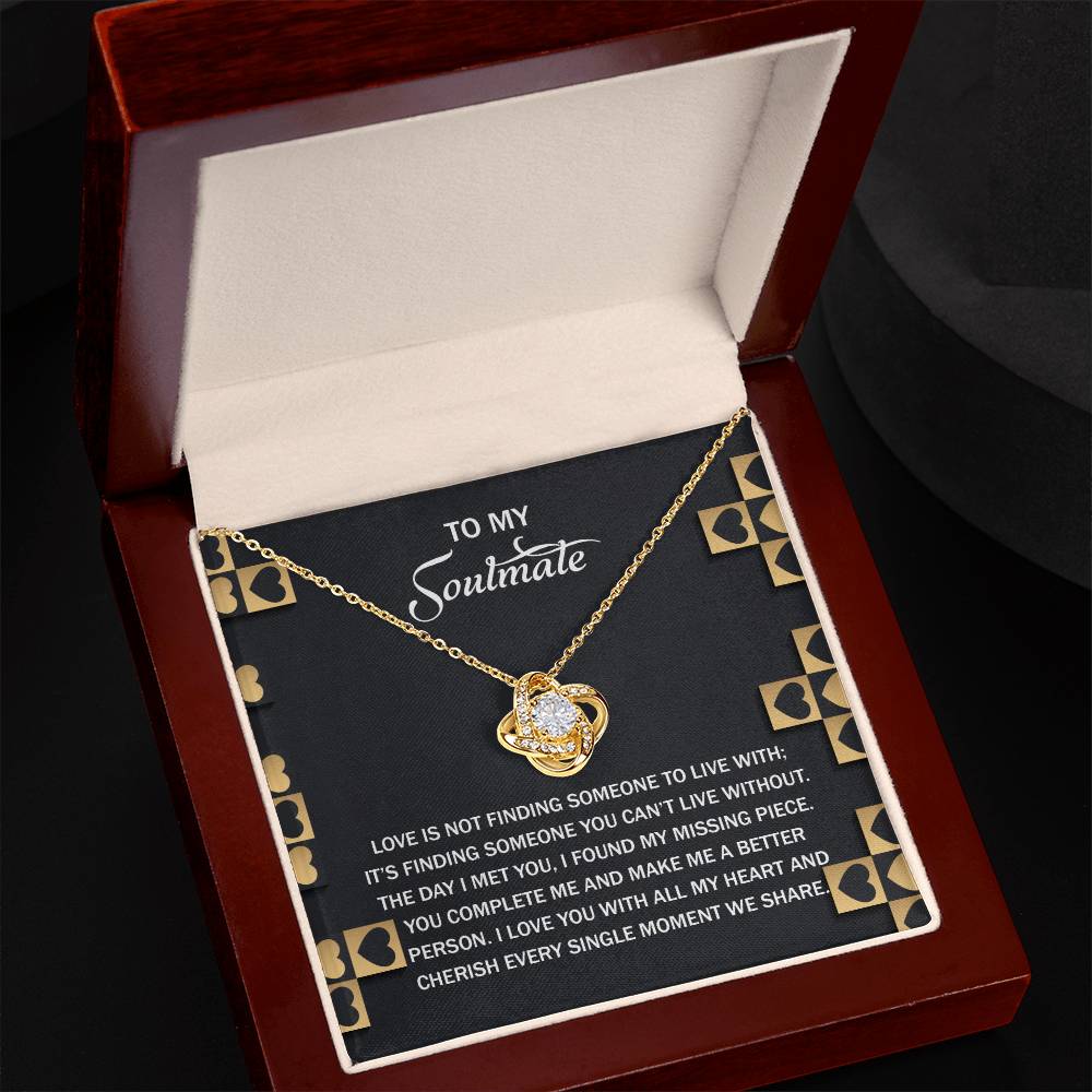 The Soulmate-Missing Piece Love Knot Necklace, featuring a gold heart adorned with cubic zirconia, rests in a jewelry box. The lid has a message about love and finding completion for a soulmate, making it an ideal personalized gift.