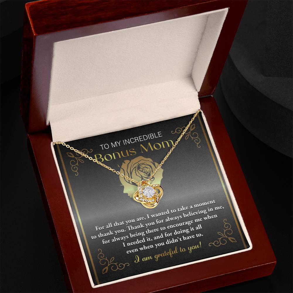 The "To Bonus Mom, To Encourage Me - Love Knot Necklace," adorned with cubic zirconia crystals, is beautifully displayed in a jewelry box. The box includes a heartfelt message expressing gratitude and appreciation to a "Bonus Mom.