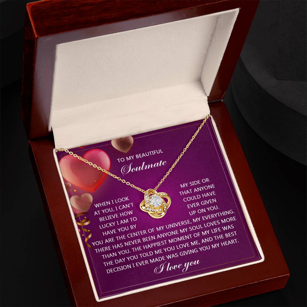 The Soulmate-My Soul Love Knot Necklace features intertwined hearts and sparkling cubic zirconia crystals, nestled in a jewelry box. Inside, a card expresses romantic sentiments about love, loyalty, and gratitude.