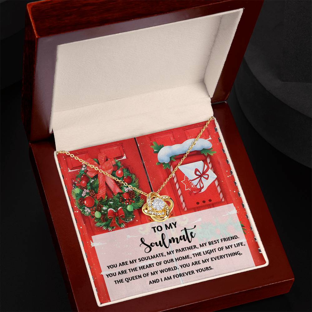 The Soulmate-Our Home - Love Knot Necklace is presented in an open wooden box, accompanied by a holiday-themed card with a heartfelt message to a soulmate. The elegant white gold finish of the pendant sparkles under the festive lights.