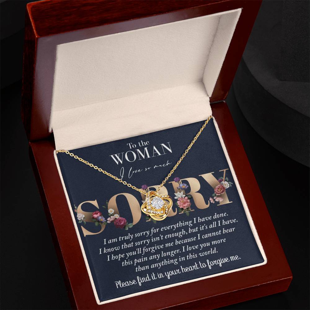 A Sorry-Bear This Pain - Love Knot Necklace rests in an open gift box, featuring a heartfelt message: "To the woman I love so much, I am truly sorry for everything I have done..." accompanied by a detailed apology below.