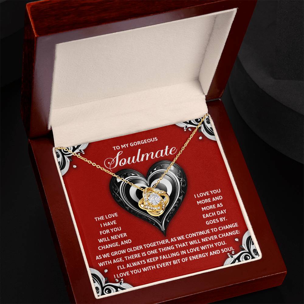 The Soulmate-Energy And Soul - Love Knot Necklace, featuring a heart-shaped pendant adorned with cubic zirconia crystals, comes in a beautiful box with a personalized romantic message for your "soulmate," set against delicate heart motifs.