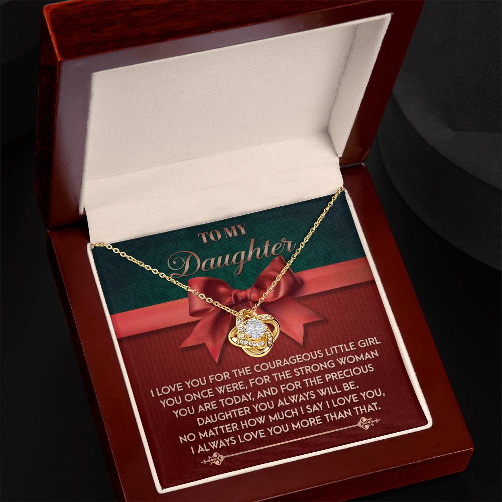 The Daughter-Always Will Be - Love Knot Necklace, featuring a gold heart-shaped pendant adorned with cubic zirconia crystals, is elegantly presented in a jewelry box. It comes with a card titled "To My Daughter" that conveys a heartfelt message about love and growth.