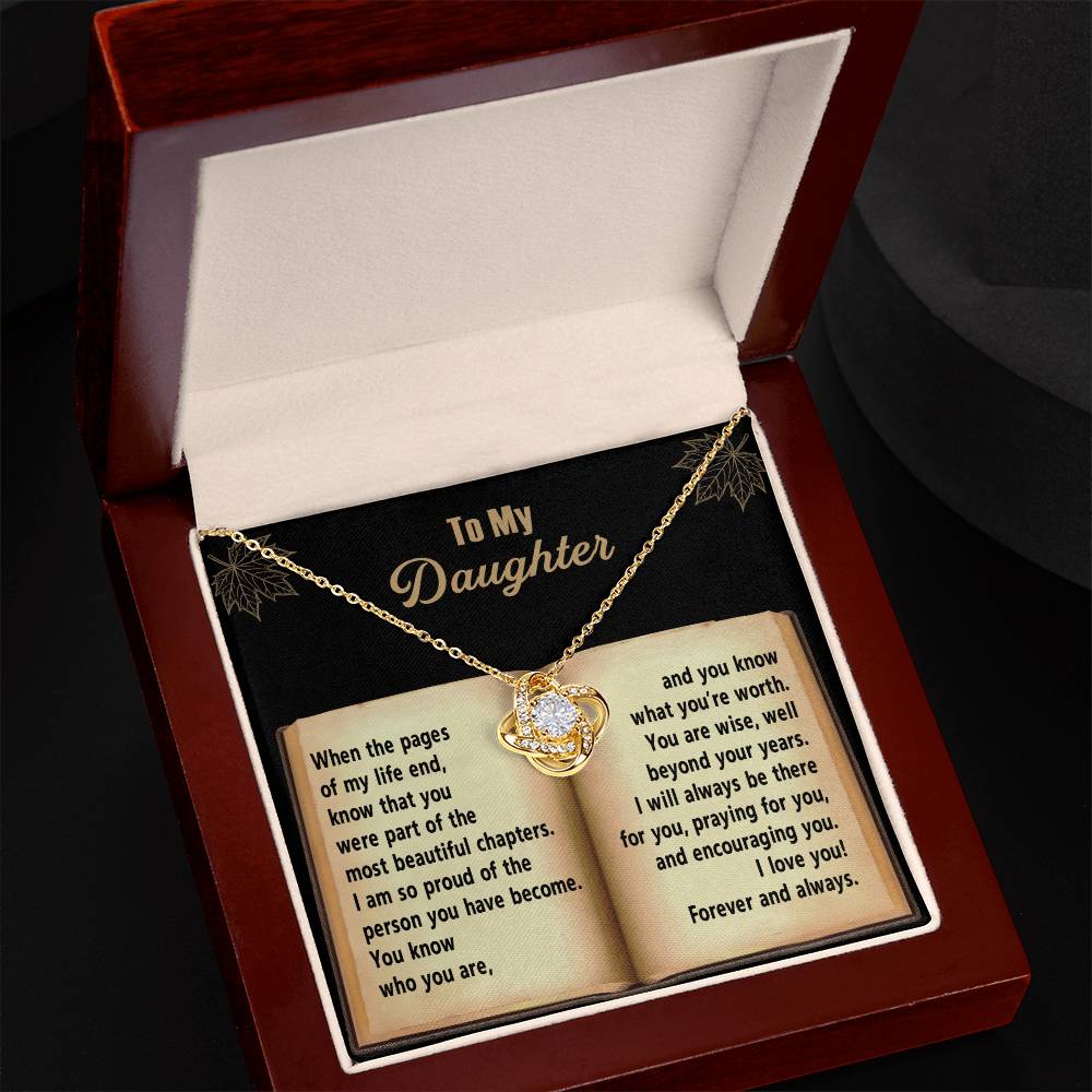 A personalized gift, the Daughter-Beyond Your Years - Love Knot Necklace features a heart-shaped pendant adorned with cubic zirconia crystals. It rests in an open box with a heartfelt message addressed to a daughter, presented in a book-like format.