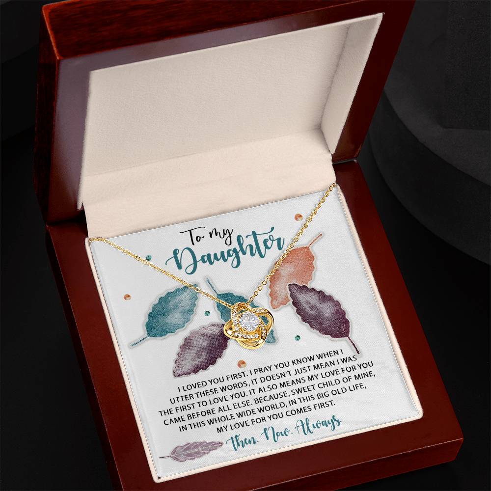 The Daughter-Pray You Know - Love Knot Necklace, crafted in 14k white gold and featuring a heart pendant, is elegantly displayed in an open wooden box. Inside, a heartfelt message begins with "To my daughter..." accompanied by a sentimental note and colorful leaf illustrations, all beautifully adorned with sparkling cubic zirconia crystals.