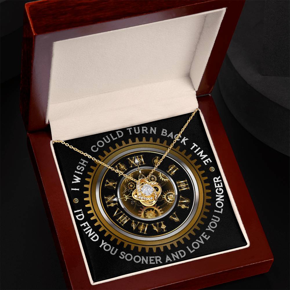 The "To Wife, Turn Back Time - Love Knot Necklace," adorned with cubic zirconia crystals, is elegantly displayed against a clock design backdrop. The text around the clock reads, "I WISH I COULD TURN BACK TIME, I'D FIND YOU SOONER AND LOVE YOU LONGER.
