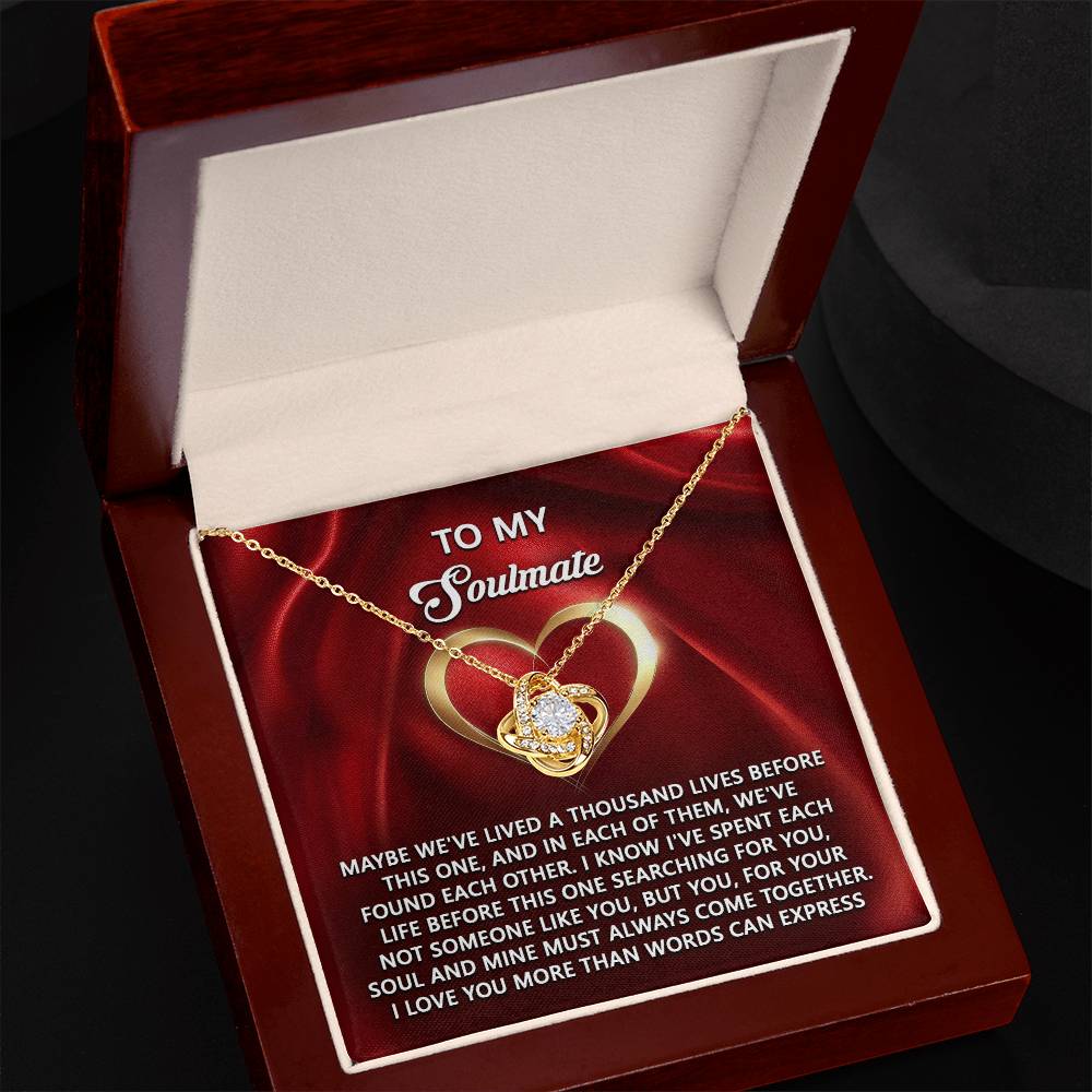 Open jewelry box with the Soulmate-Your Soul - Love Knot Necklace featuring a gold intertwined heart and ribbon design. The centerpiece sparkles with cubic zirconia, and the box lid carries an affectionate message to a soulmate, making it an ideal personalized gift.