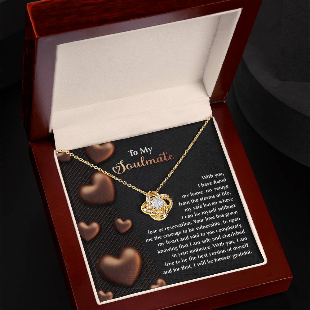 The Soulmate-Best Version Love Knot Necklace, embellished with a heart and cubic zirconia crystals, is elegantly displayed in an open jewelry box against a backdrop of romantic messages and heart designs—ideal for a personalized gift.